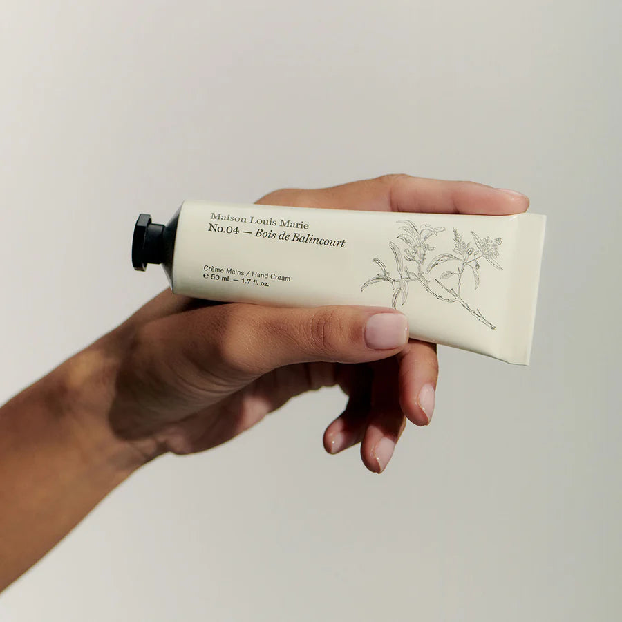 Hand holding a tube of hand cream with a white background