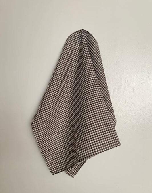 A brown and white checkered linen tea towel hanging on a wall.