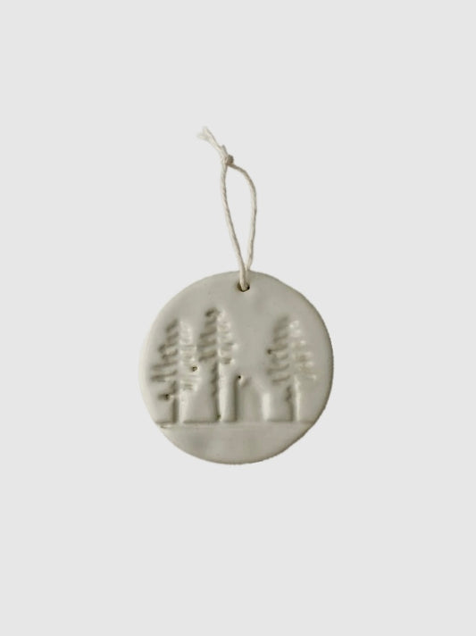 Round ceramic ornament with tree design on a white background