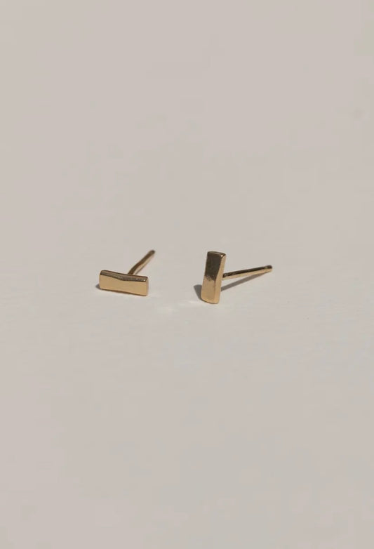 Gold bar stud earrings on a light gray background