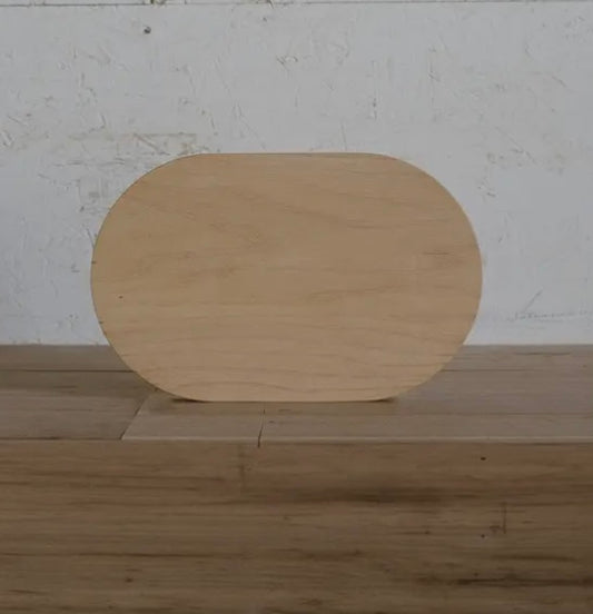 Oblong shaped wooden cutting board placed on a wooden surface.