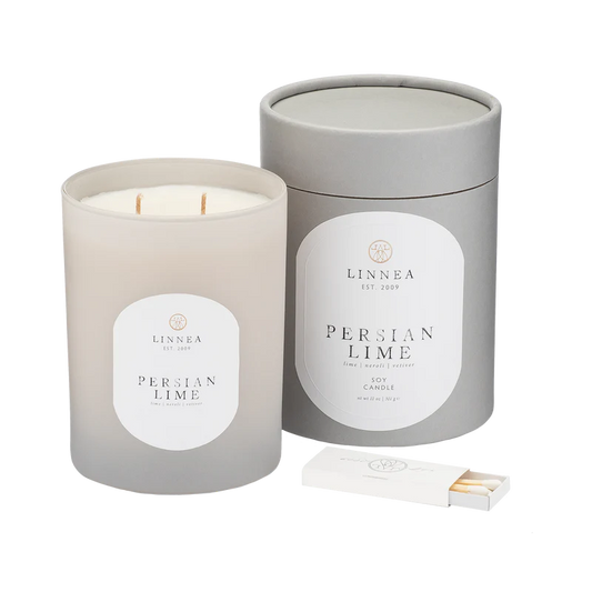 A LINNEA soy candle handcrafted in small batches, with a double cotton wick, in a gray container with the label 'Persian Lime'. A matchbox is included in the image.