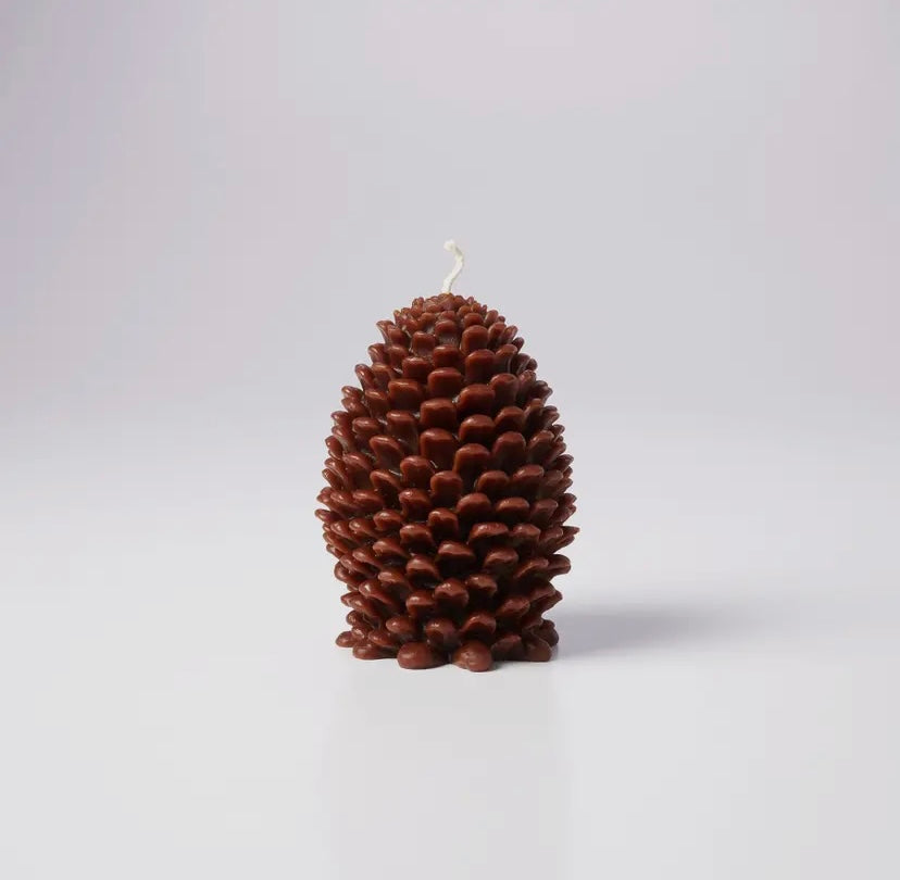 Pine cone-shaped beeswax candle on a light gray background