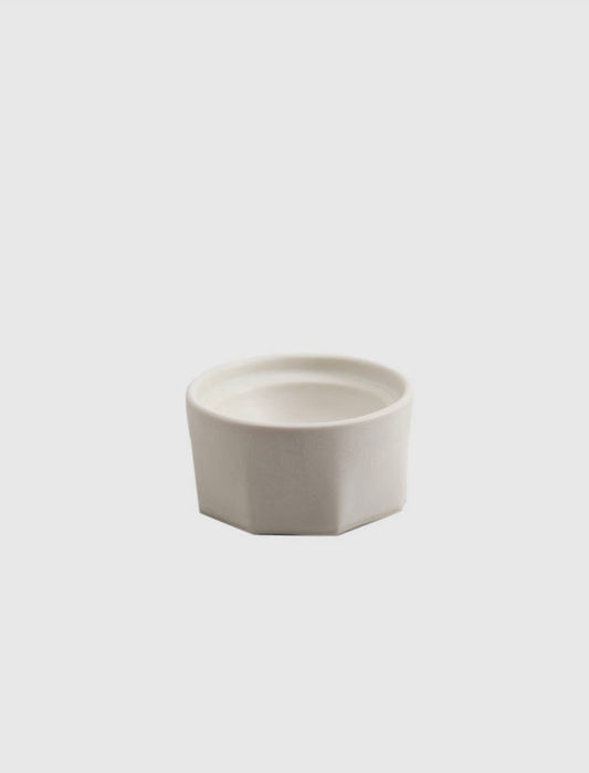 Close-up of porcelain salt cellar showing faceted texture and spherical interior.

