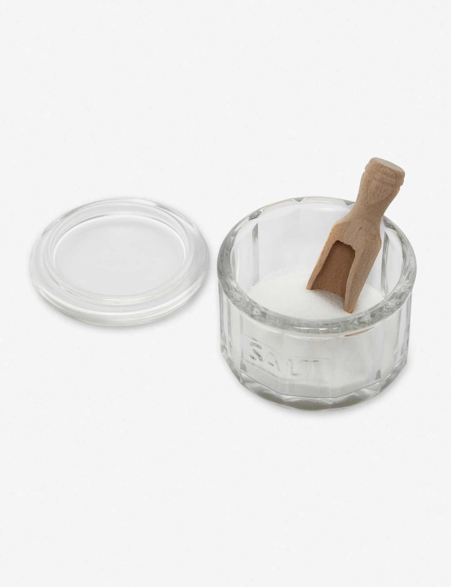 Vintage-style glass salt pot with wooden scoop on kitchen counter.