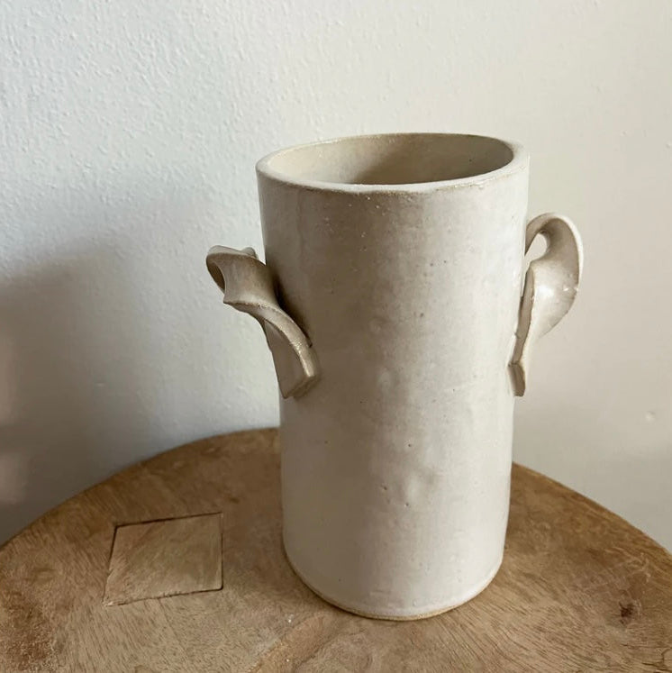 Beige ceramic vase with handles on a wooden surface