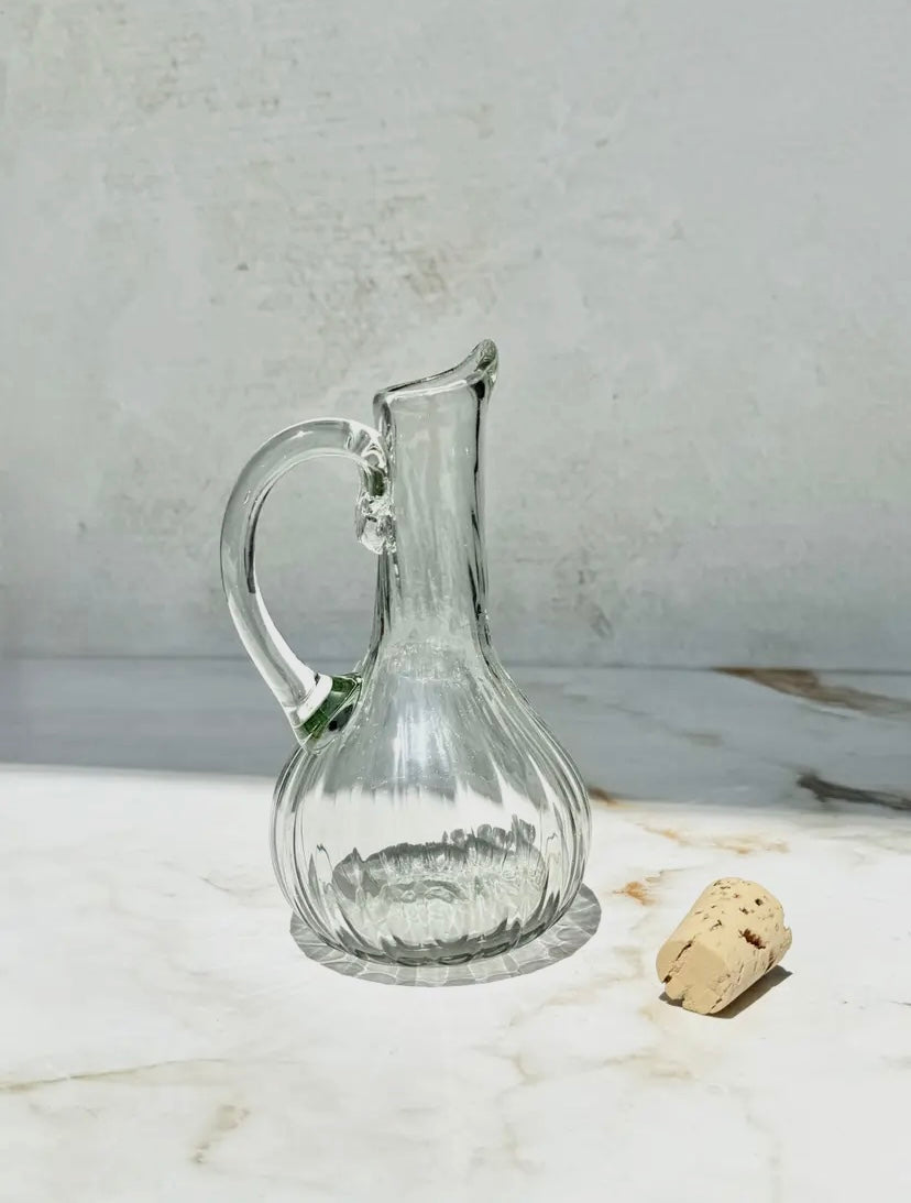 Clear glass cruet on a marble surface with a cork.