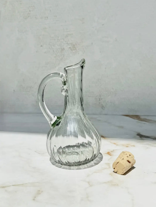 Clear glass cruet on a marble surface with a cork.