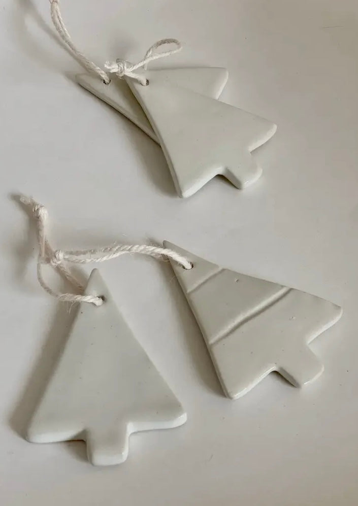 Three white ceramic Christmas tree ornaments on a light gray background