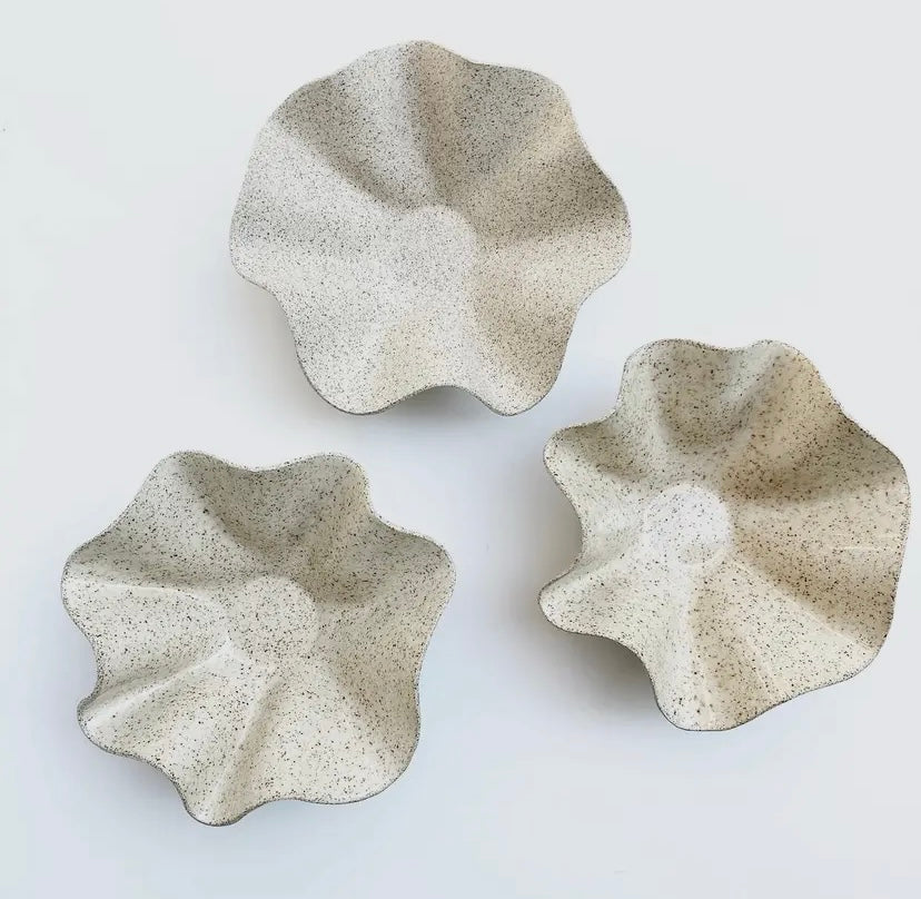 Two white ceramic ruffle bowls of different sizes placed on a neutral surface.