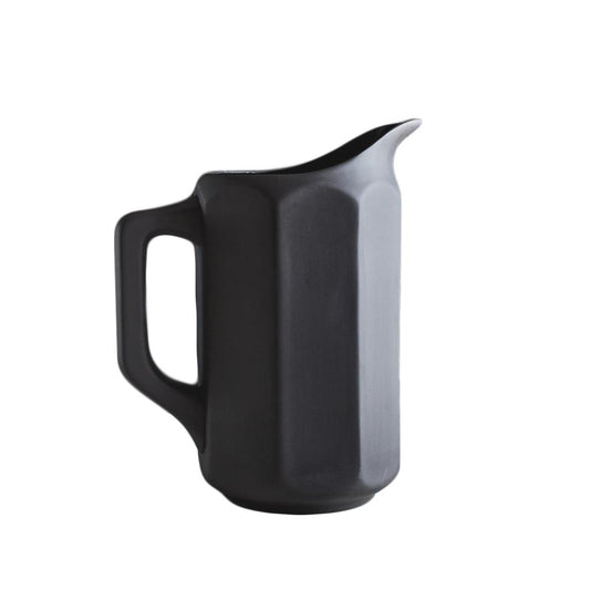 Large black ceramic pitcher on a with octagonal paneled sides.