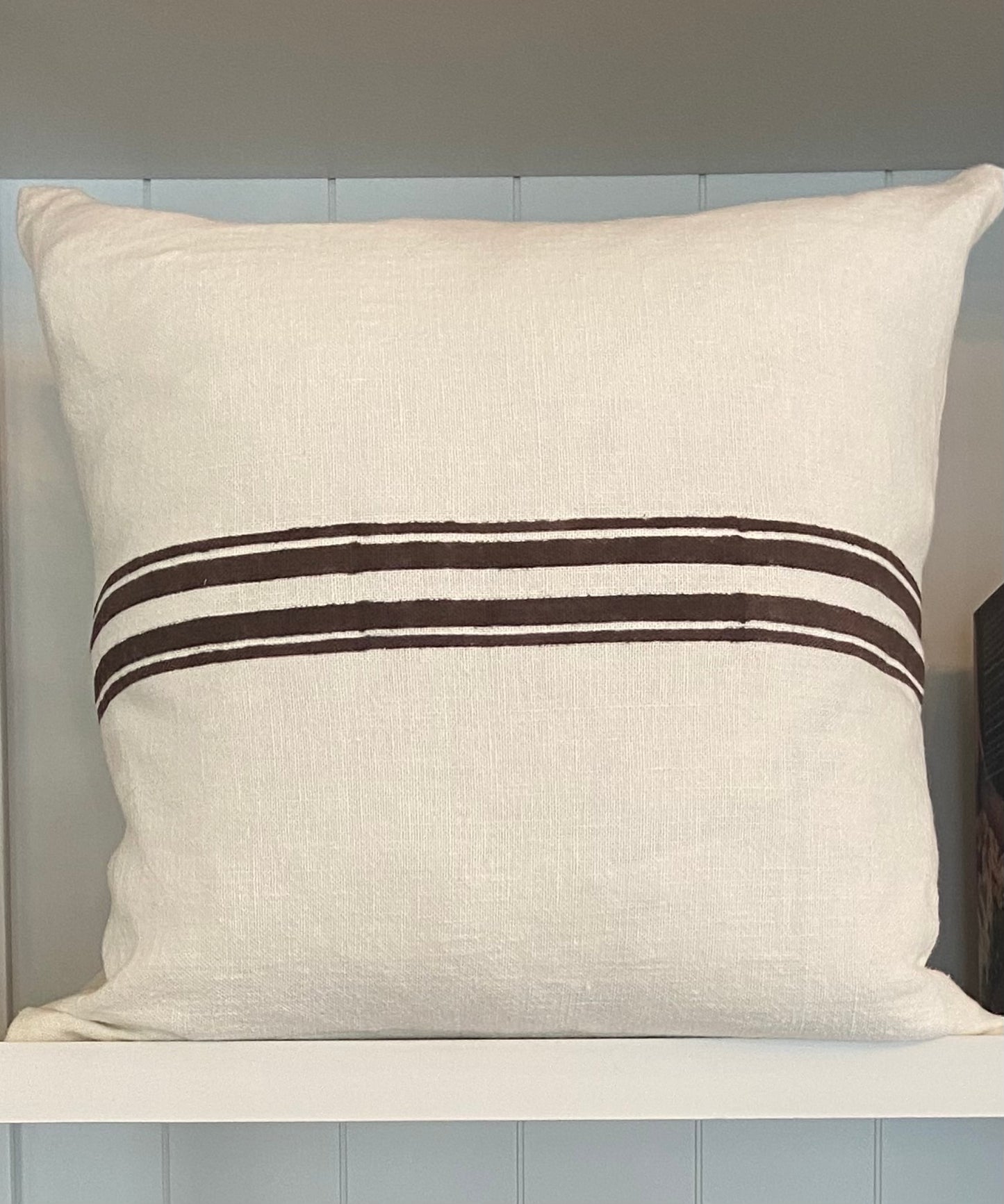 Beige pillow with two brown stripes on a wooden surface
