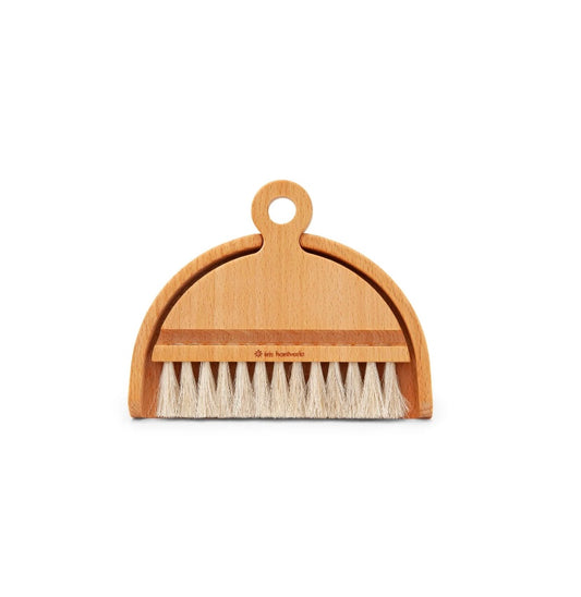 A beige table brush with soft bristles and an oval wooden handle, branded by Iris Hantverk.