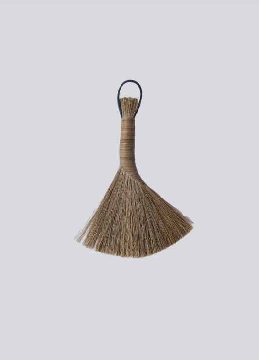 Brown horsehair brush with a black handle on a light gray background