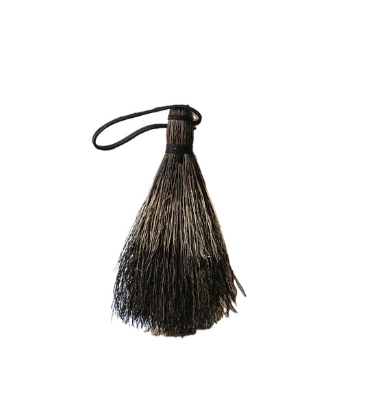 A naturally dyed brush with black hemp and leather tie, against a white background.