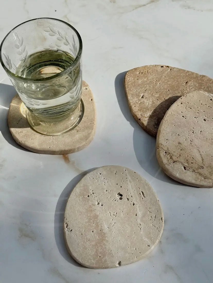 Set of stone coasters with a glass of water on a marble surface