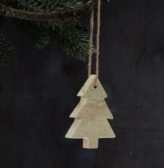 Decorative stone Christmas tree ornament hanging from a branch against a dark background