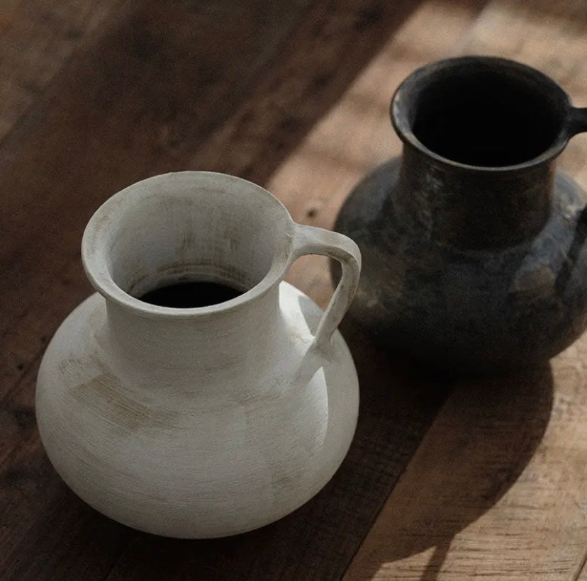 Two wabi sabi ceramic vases on a wooden table viewed from above.