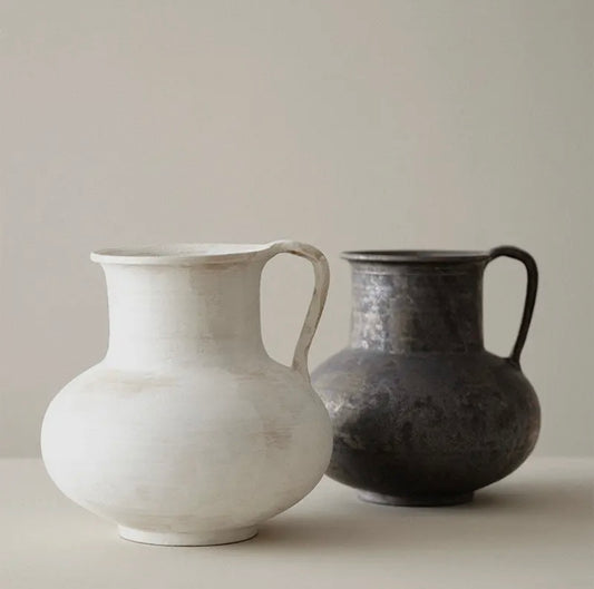 Two wabi sabi ceramic jugs, one white and one black, on a neutral background