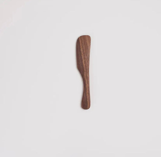 Wooden walnut spreader on a light gray background