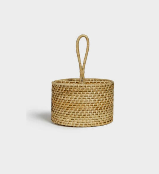 A cylindrical rattan utensil caddy with a handle, displayed against a neutral background.