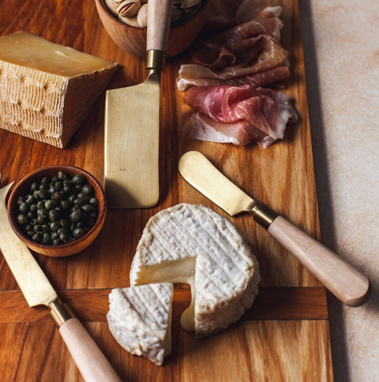 Cheese knive set displayed with meets and cheeses.