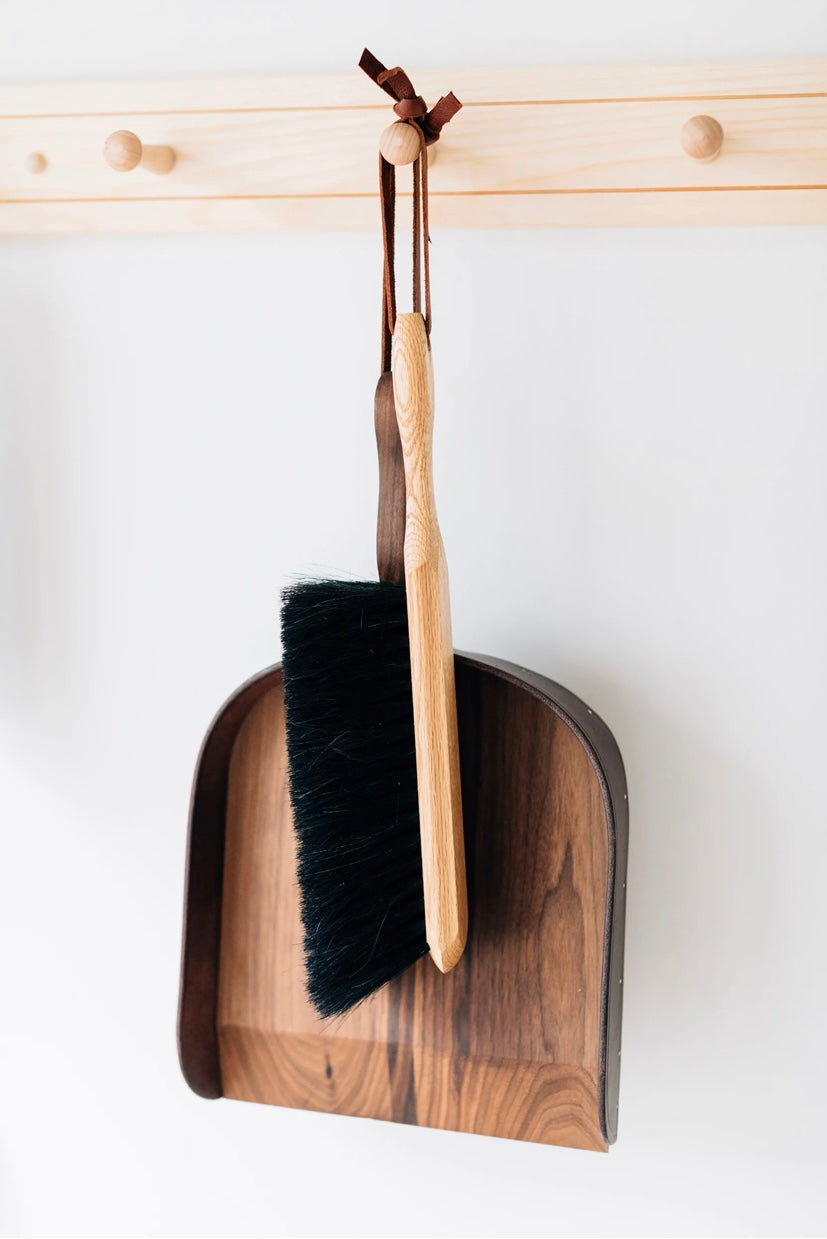 Horsehair brush displayed with leather and walnut dustpan.